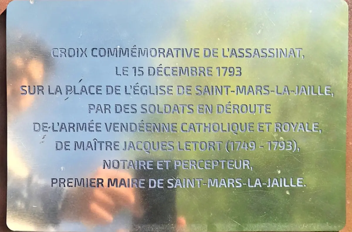 La plaque commémorative au pied de la croix : elle date l'assassinat du 15 décembre 1793 et l'attribue à des soldats en déroute de l'armée vendéenne.