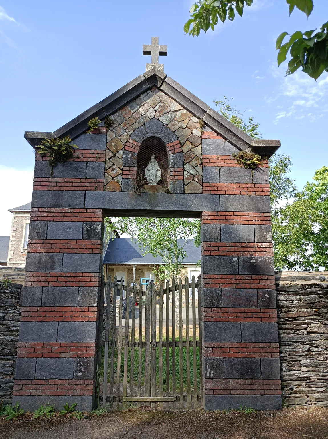L'ancienne porte d'entrée de l'école Sainte-Anne : brique et schiste, fronton surmonté d'une croix et niche abritant la Vierge.