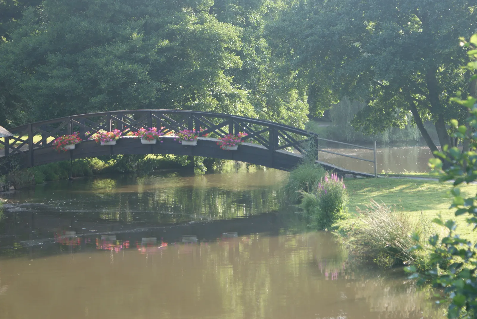 La grande passerelle de bois enjambe l'Erdre, fleurie chaque été : reconstruite en 1991 d'après les dessins de Louis Baranger, elle se reflète dans le miroir d'eau au petit matin.