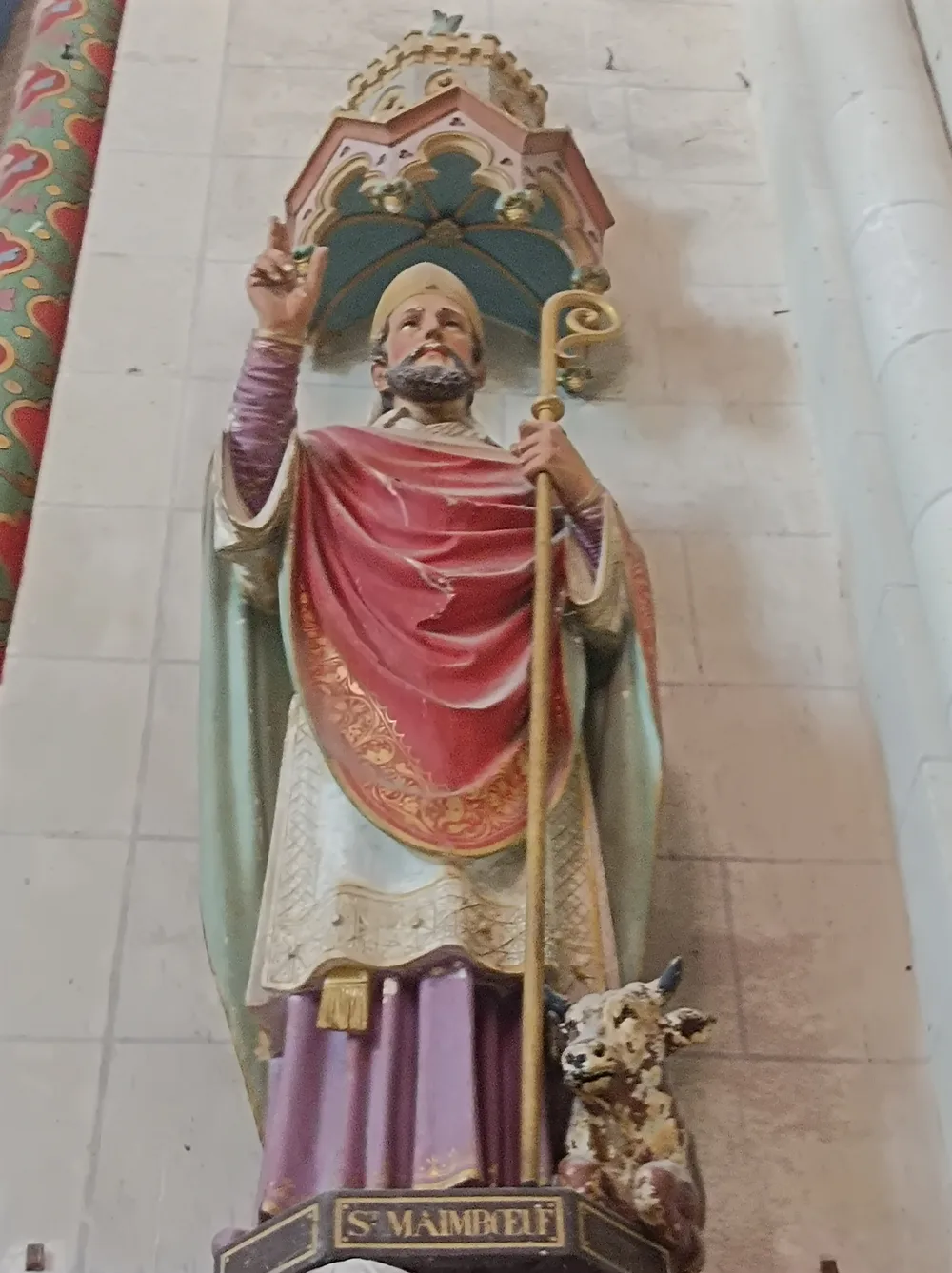 Statue polychrome de saint Maimbœuf, évêque d'Angers, dans l'église de Freigné : le taureau couché à ses pieds est son attribut.